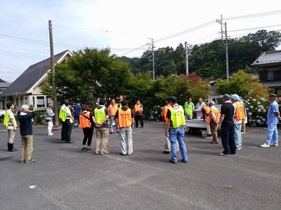 大勢の人が住宅前にある広い駐車場のようなところに集まっている写真