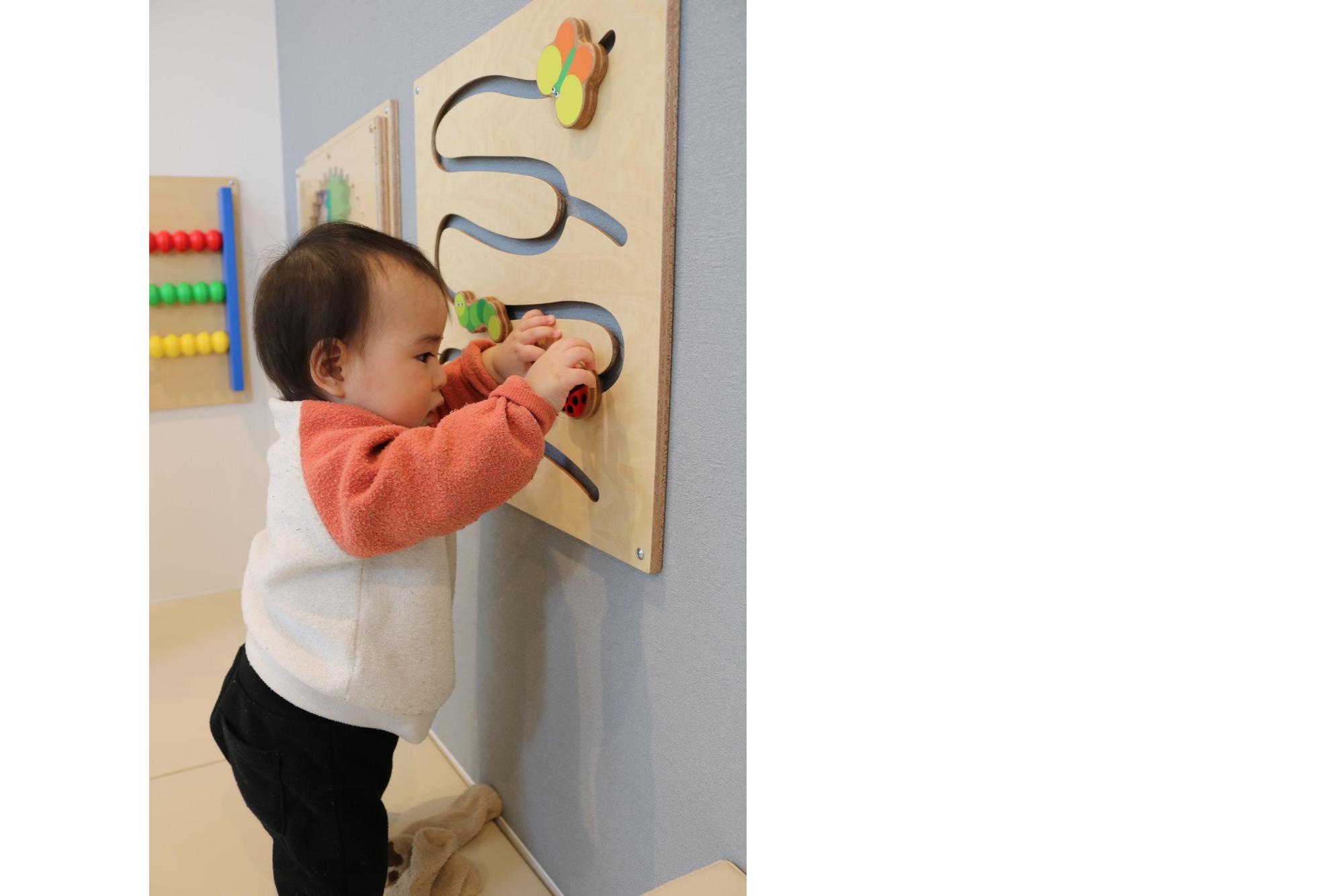 壁玩具で遊ぶ乳児