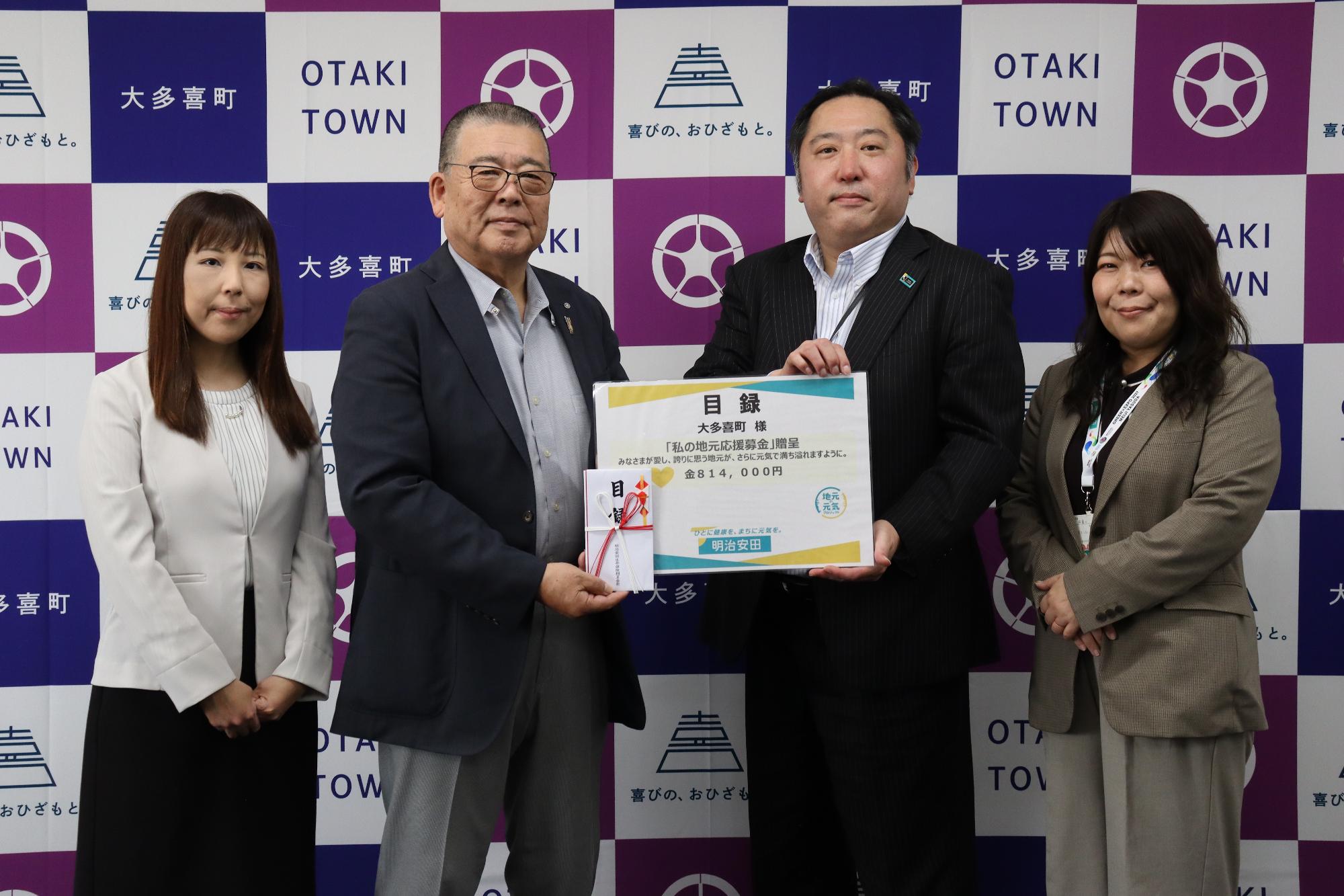平林貯町が明治安田生命営業部長より目録を受け取っている